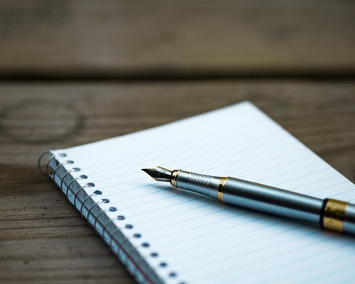 Notebook and pen on a wooden desk ready for feedback